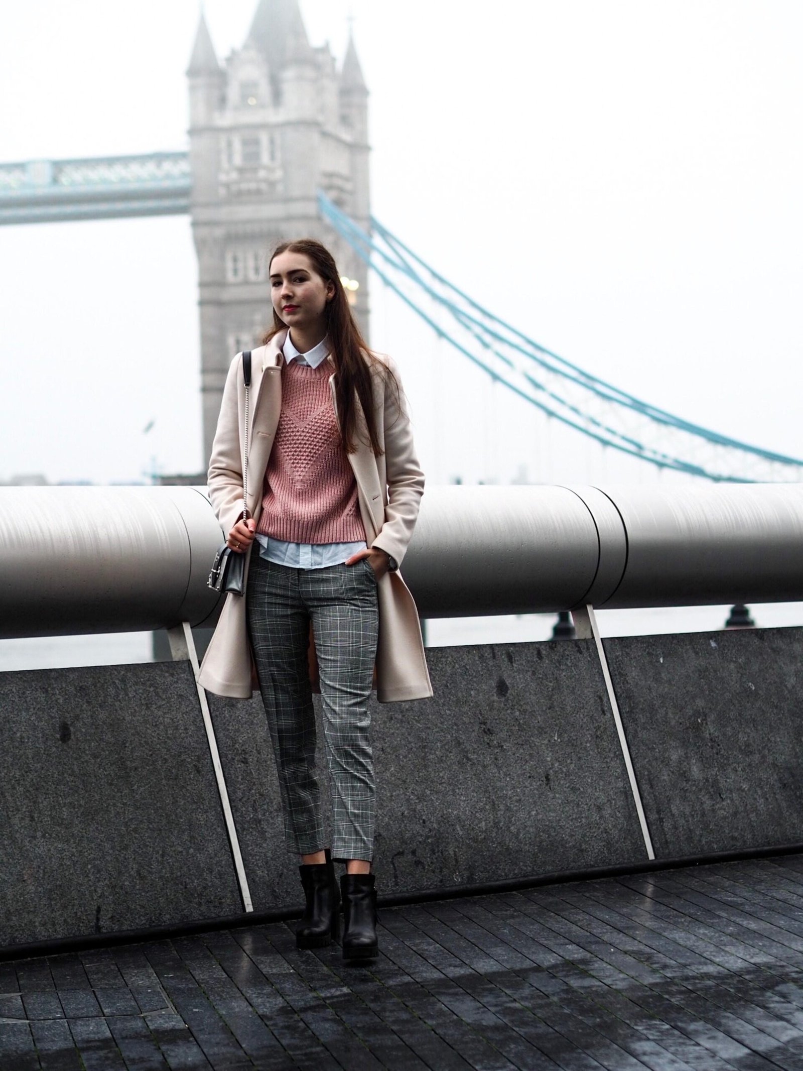 woman in brown overcoat near Tower Bridge